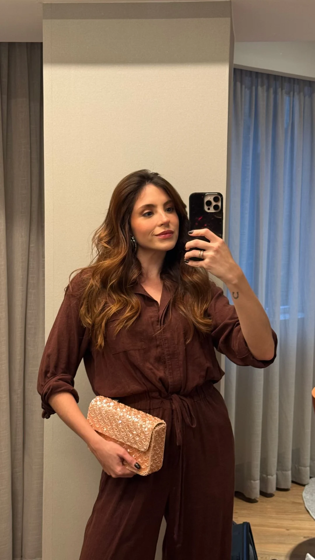 Rafaela de conjunto marrom e bolsa, em registro no espelho durante o SPFW